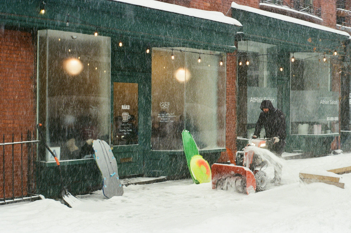 Snowblower clearing a sidewalk during a snowfall